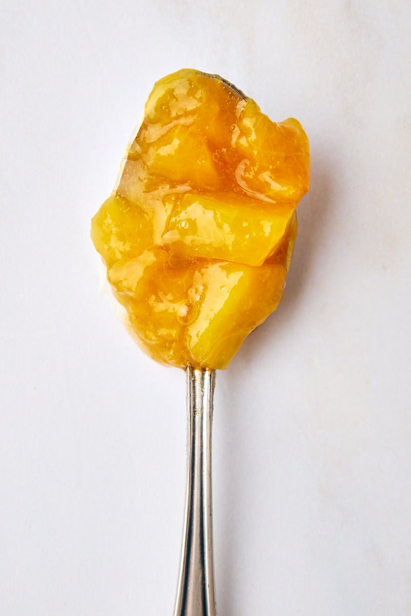 a spoonful of peach compote on a white surface
