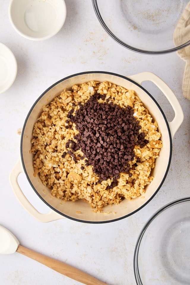 overhead view of chocolate chips added to s'mores rice crispy treat mixture in a saucepan
