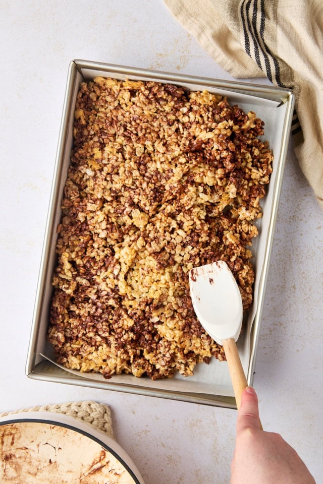 overhead view of s'mores rice crispy treats being spread in a 9x13 pan