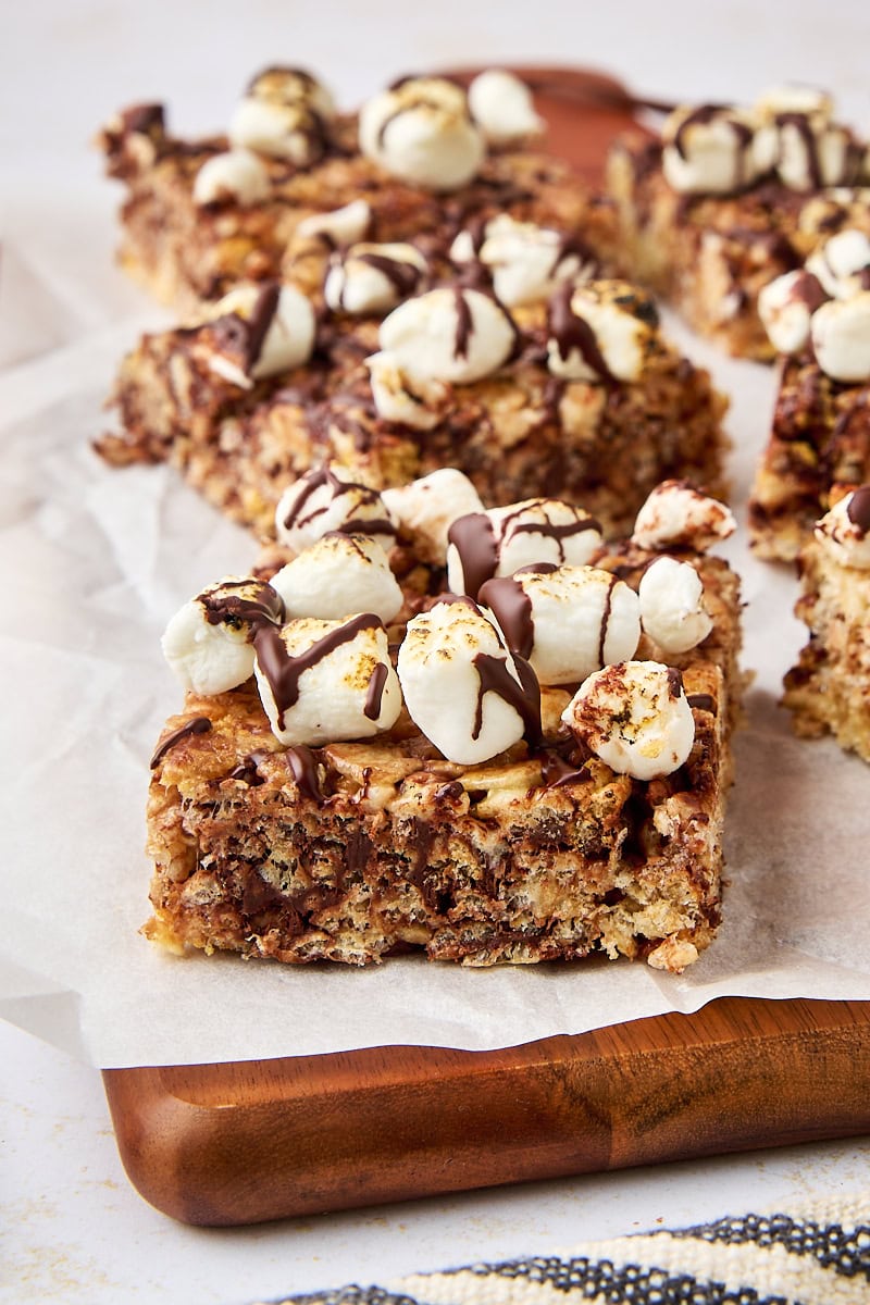 s'mores rice crispy treats on a wooden cutting board lined with parchment paper