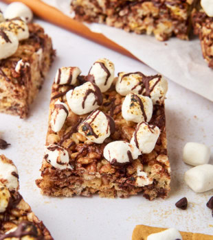 a s'mores rice crispy treat on a white surface surrounded by more bars