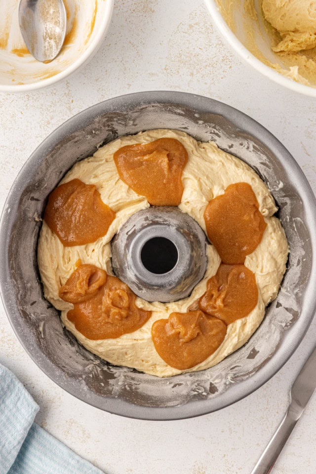 overhead view of caramel mixture spooned over vanilla cake batter in a Bundt pan
