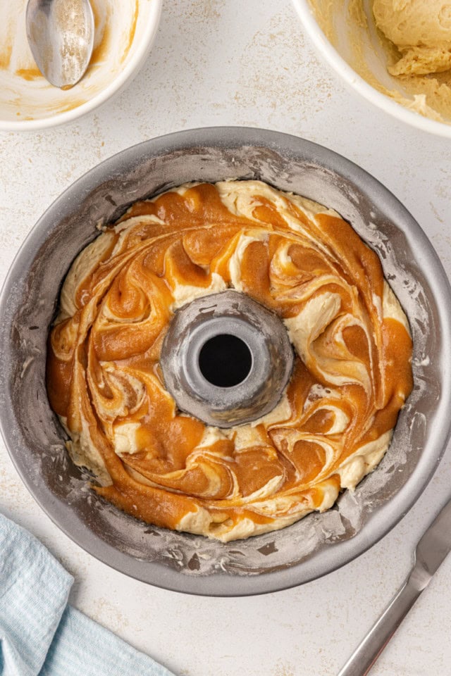 overhead view of caramel mixture swirled into vanilla cake batter in a Bundt pan