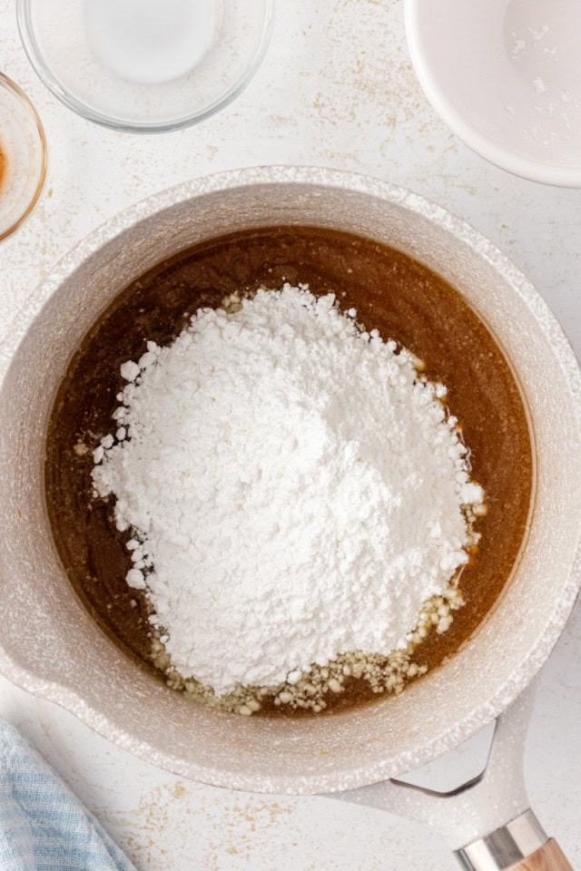 overhead view of confectioners' sugar added to caramel glaze mixture