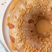 overhead view of caramel swirl Bundt cake topped with caramel glaze on a white cake plate