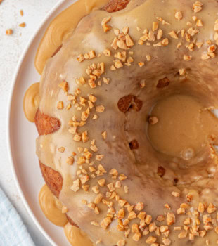 overhead view of caramel swirl Bundt cake topped with caramel glaze on a white cake plate