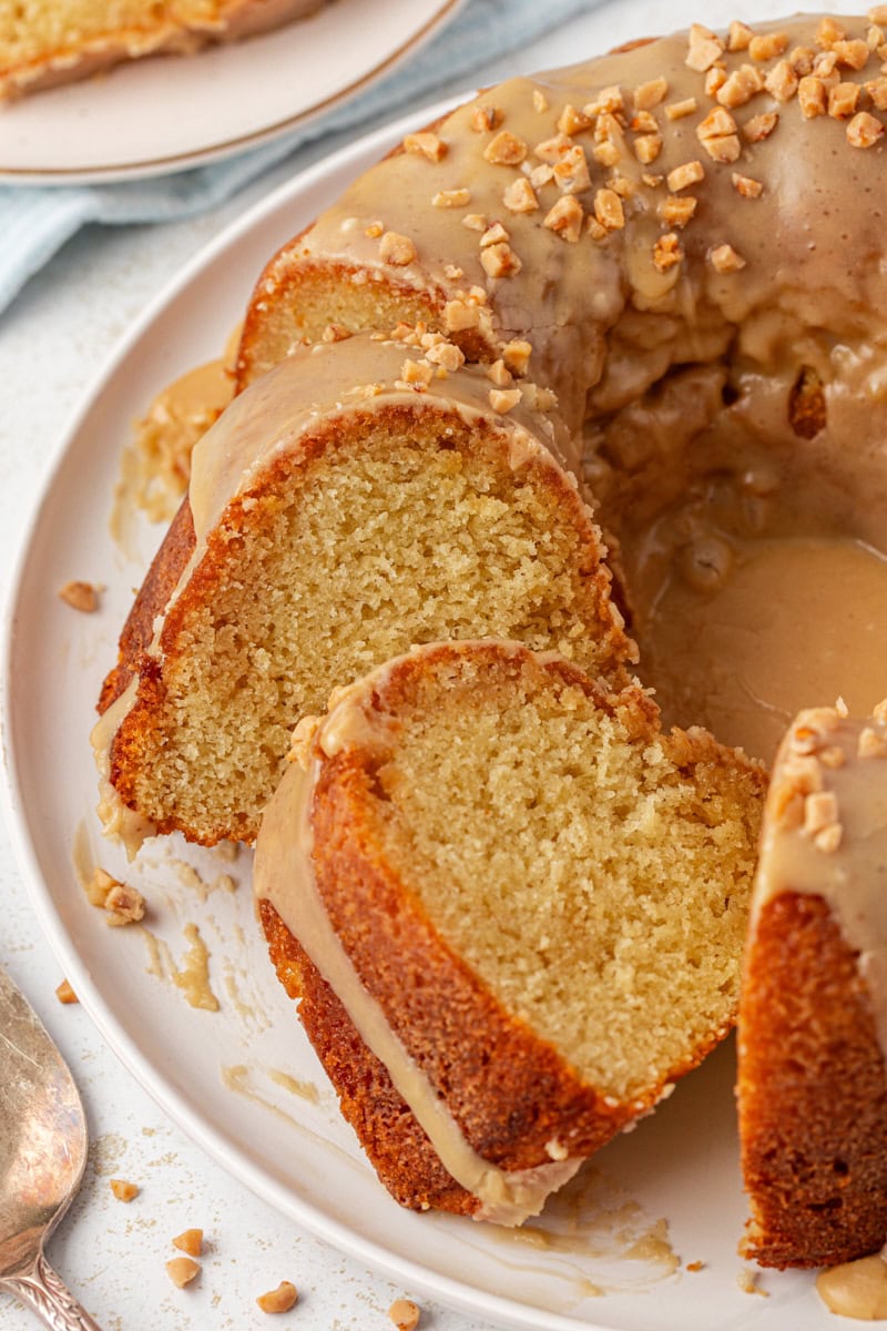 partially sliced caramel swirl Bundt cake on a white cake plate
