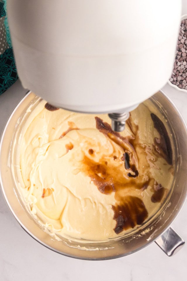 overhead view of vanilla and almond extracts added to cake batter in the bowl of stand mixer