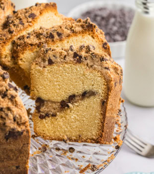 partially sliced chocolate chip crumb pound cake on a glass cake plate