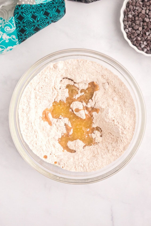 overhead view of flour, brown sugar, sugar, cinnamon, and melted butter in a glass mixing bowl