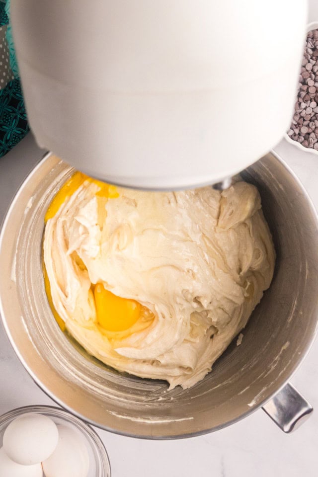 overhead view of eggs added to creamed butter and sugar in the bowl of a stand mixer