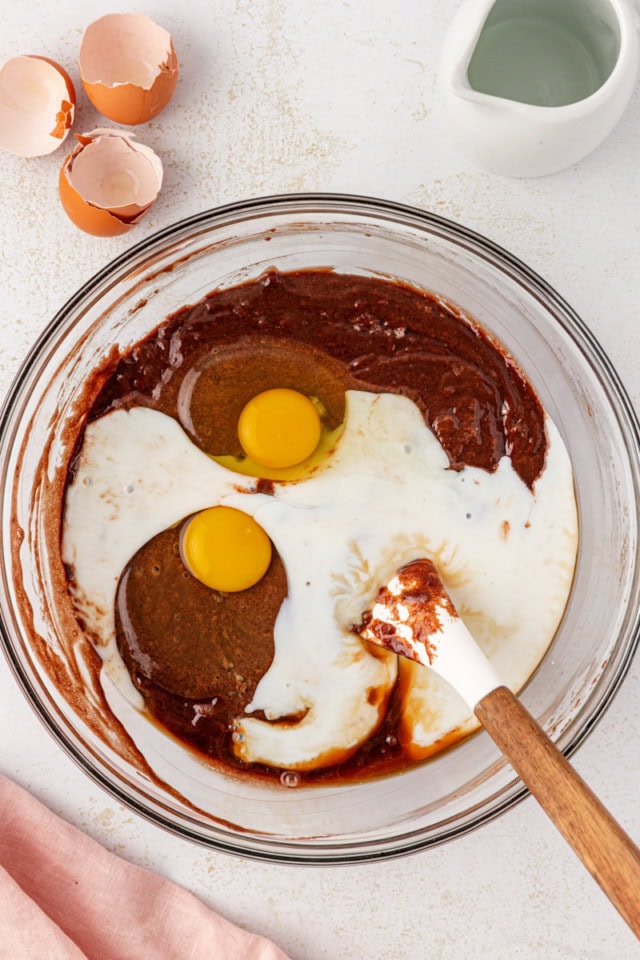 overhead view of eggs, buttermilk, and vanilla added to chocolate cake batter