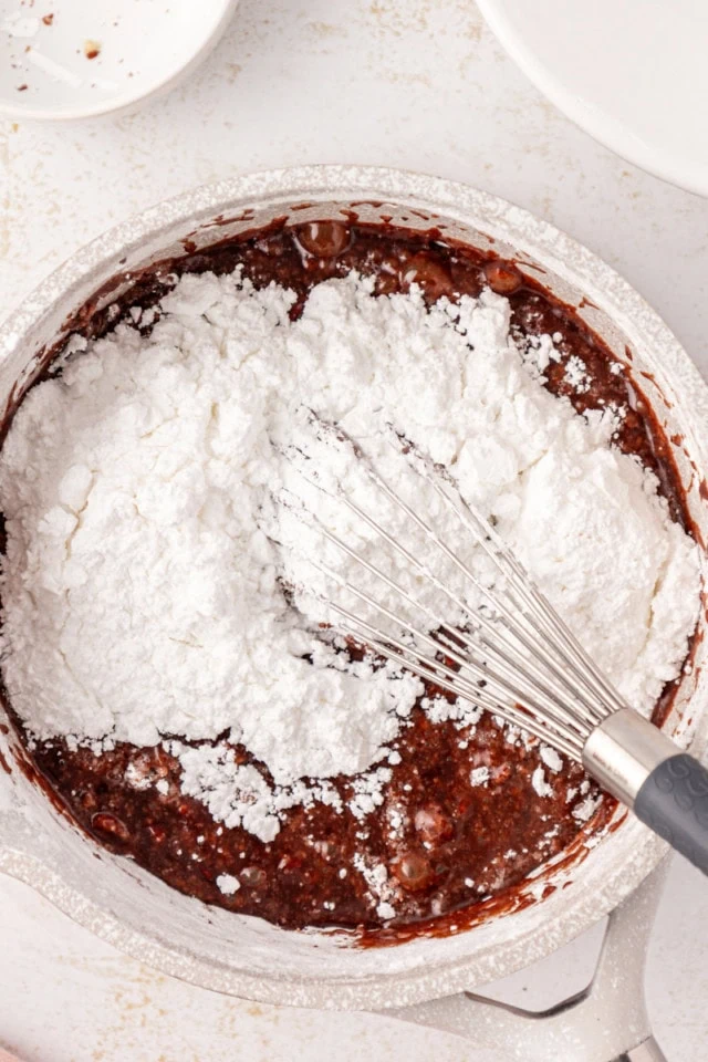 overhead view of confectioners' sugar, vanilla, and salt added to melted butter, milk, and cocoa mixture