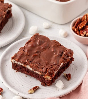 a slice of Mississippi mud cake on a white plate with more cake in the background