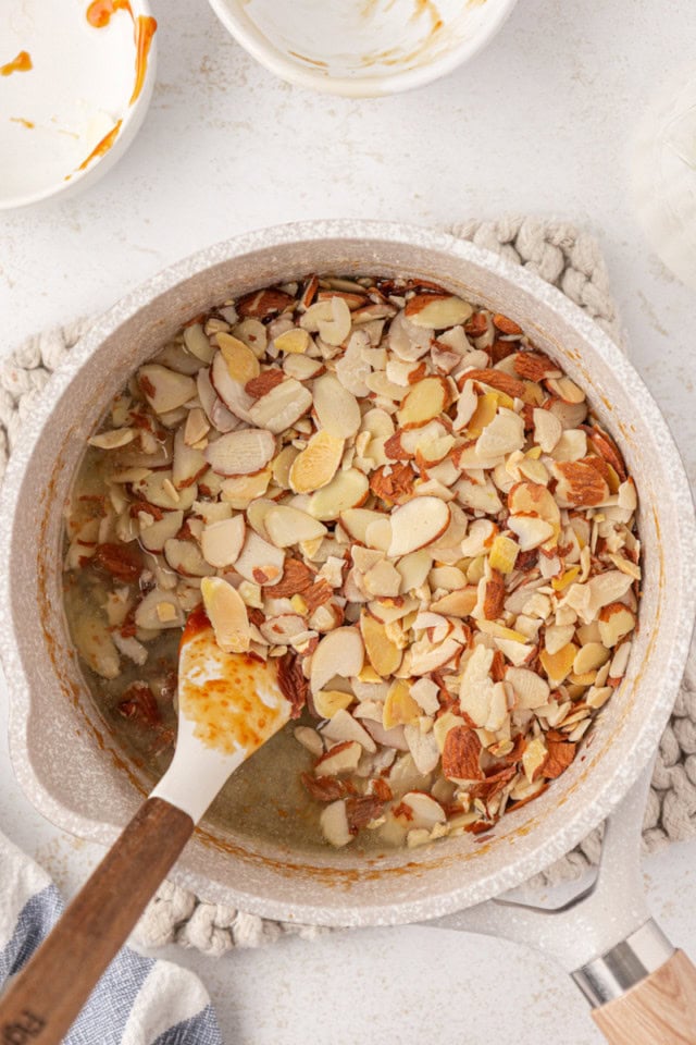 overhead view of almonds added to caramel in a saucepan