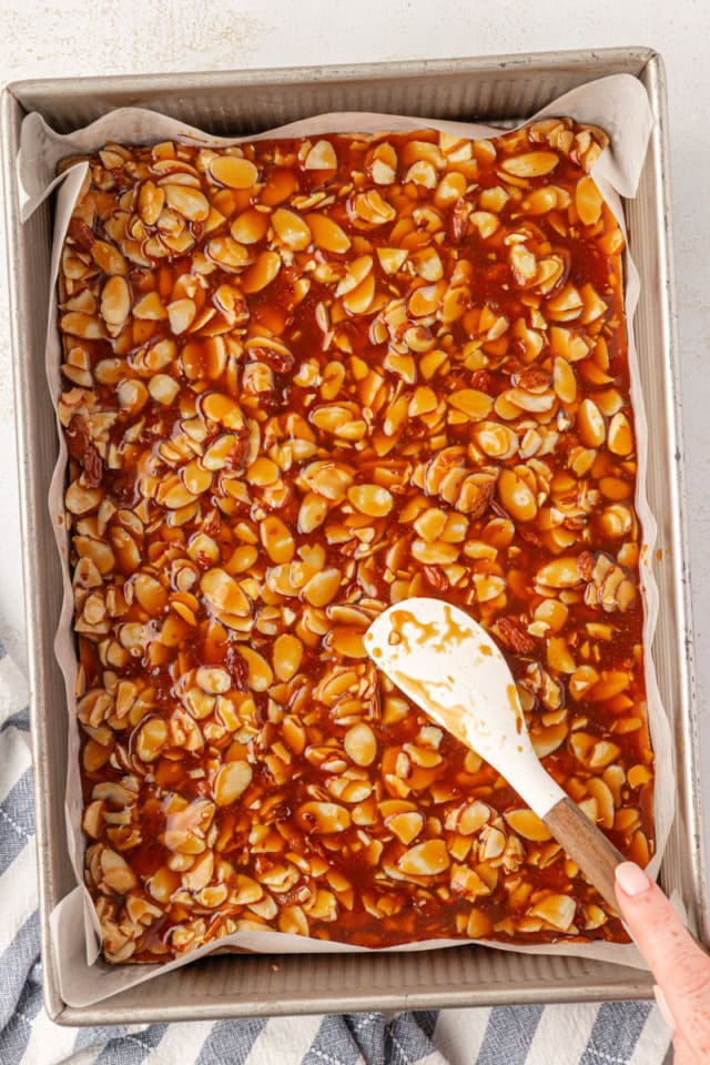 overhead view of topping being spread over parbaked shortbread crust in a 9x13 pan