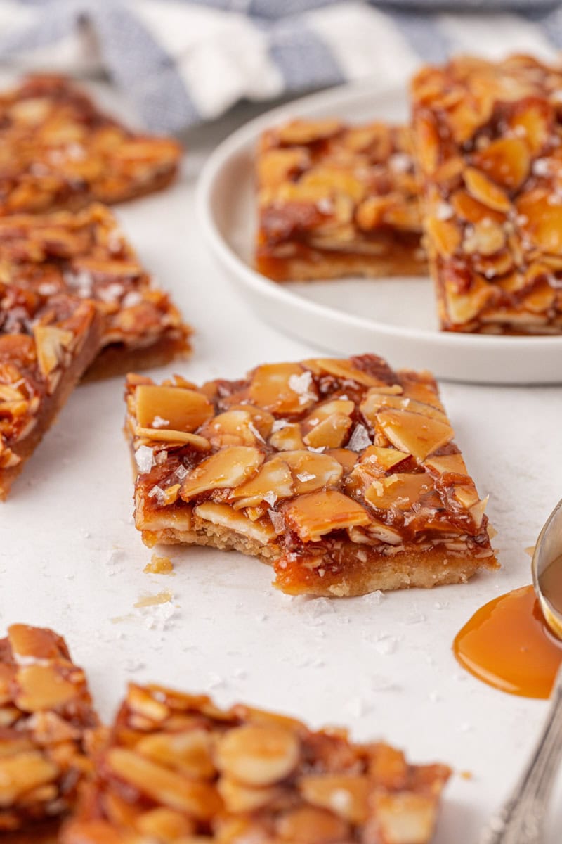 a salted caramel almond bar with a bite missing, surrounded by more bars