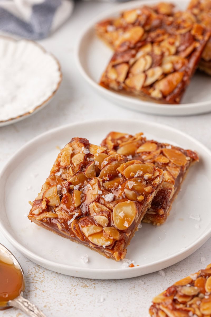 two salted caramel almond bars on a white plate with more bars surrounding