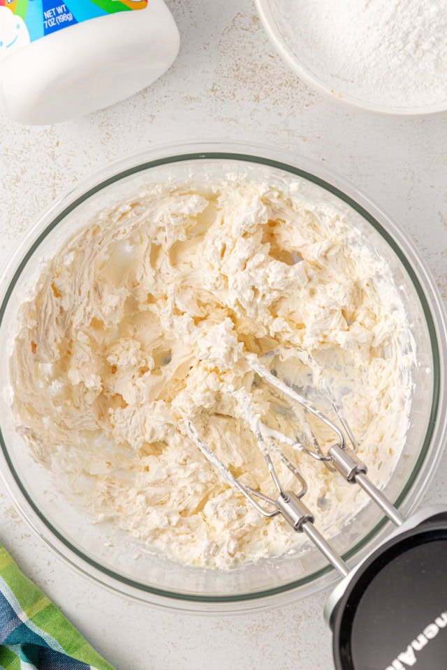 overhead view of beaten butter, marshmallow creme, and vanilla in a glass mixing bowl