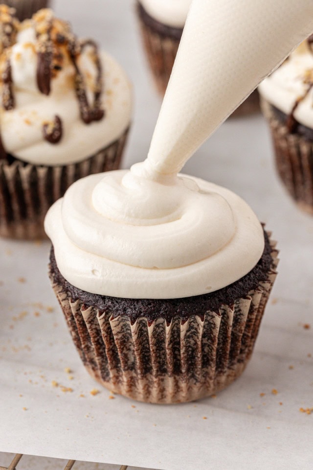 marshmallow frosting being piped onto a s'mores cupcake