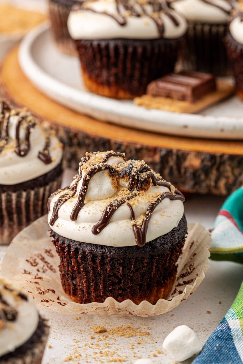 a s'mores cupcake sitting on its peeled-away wrapper with more cupcakes in the background