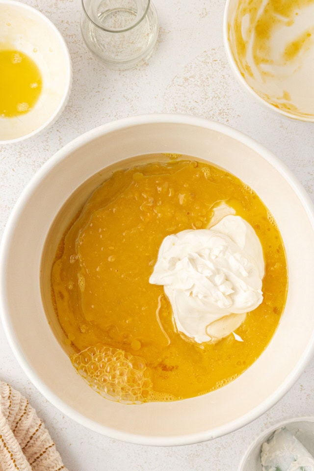 overhead view of eggs, oil, sour cream, and corn in a white mixing bowl