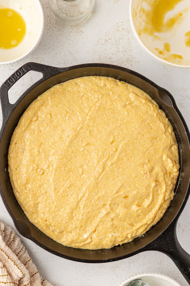 overhead view of sour cream corn bread batter in a cast iron skillet ready to go into the oven