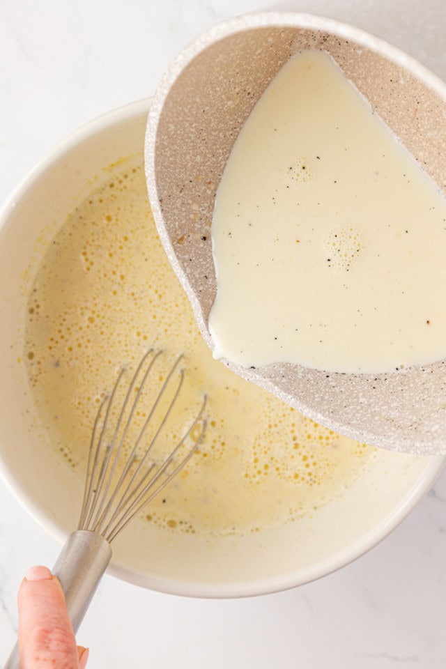 overhead view of heated cream mixture being poured into egg yolk mixture for vanilla bean pots de crème