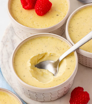 vanilla bean pots de crème on a marble serving tray with fresh raspberries