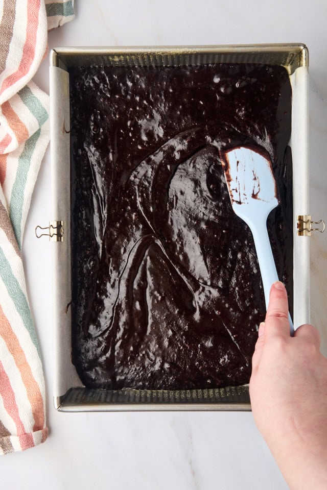 overhead view of brownie batter being spread in a 9x13 pan