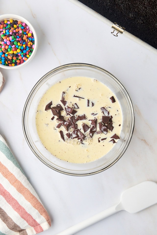 overhead view of cream poured over chopped semisweet chocolate in a glass bowl