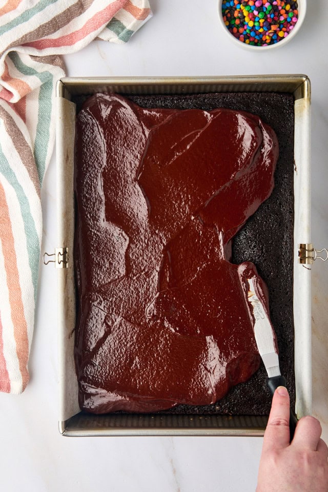 overhead view of ganache being spread over brownies in a 9x13 pan
