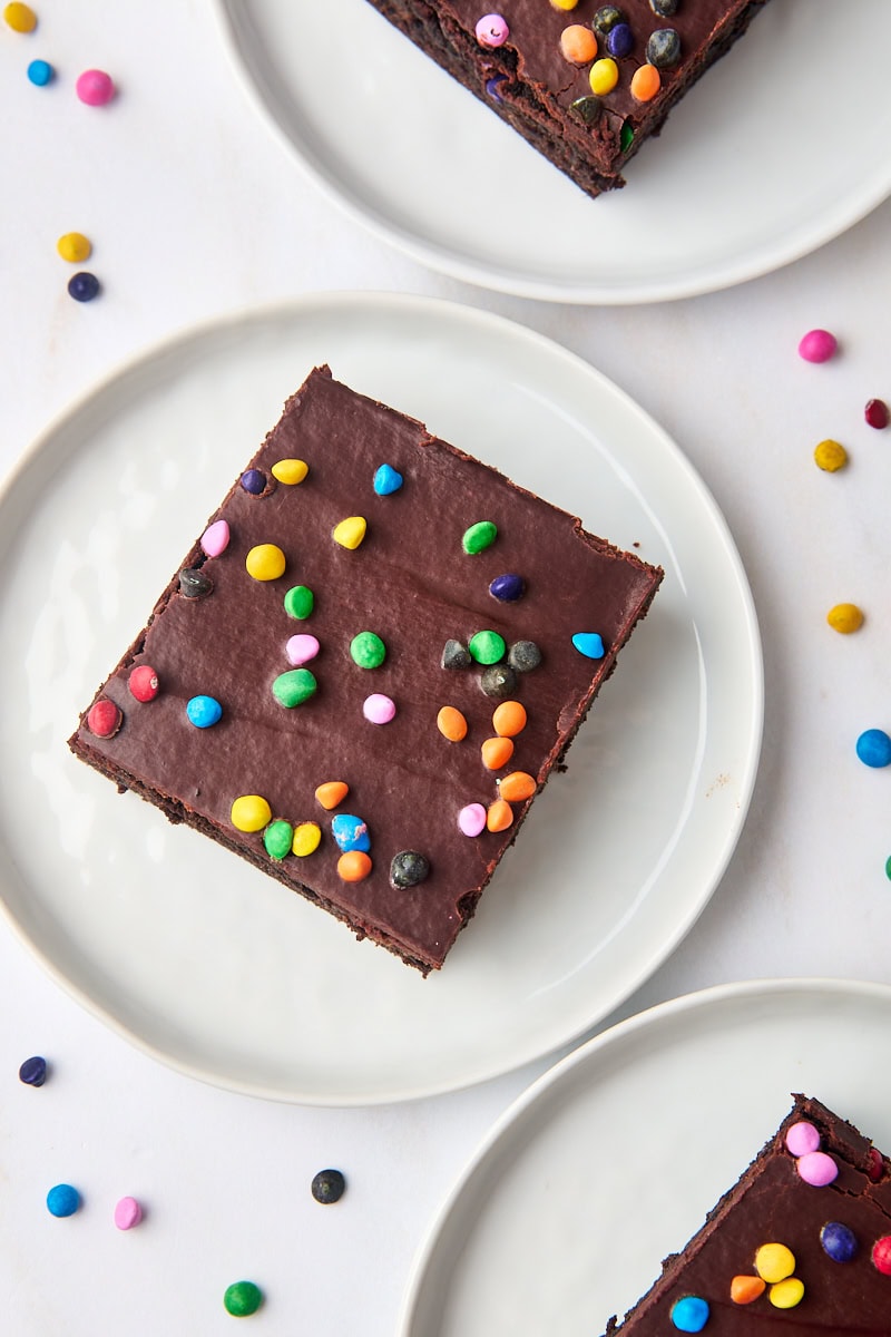 overhead view of a cosmic brownie on a white plate with two more brownies on plates partially visible