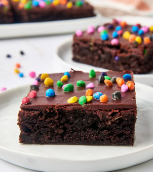 a cosmic brownie on a white plate with more brownies in the background