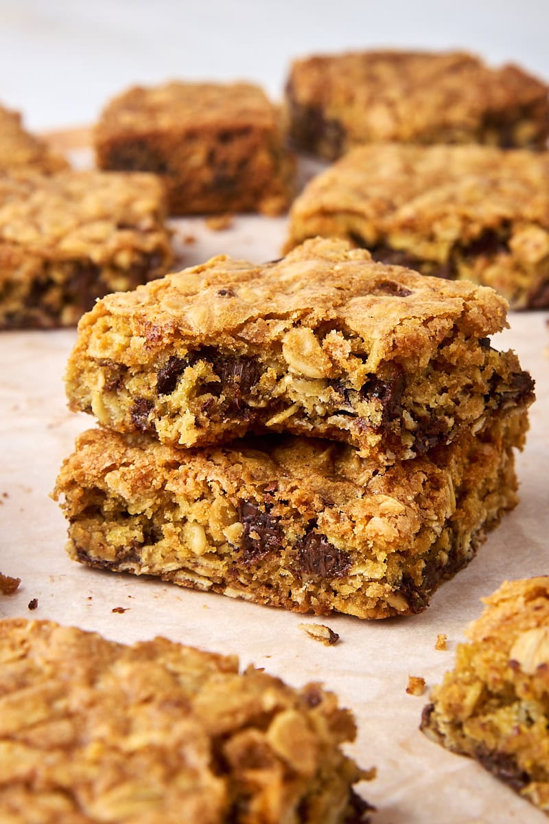 stack of two oatmeal cookie bars with a bite missing from the top bar; more bars surrounding