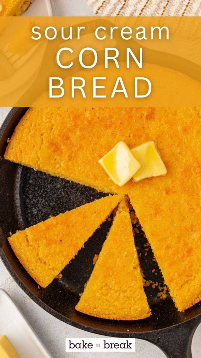 overhead view of partially sliced sour cream corn bread topped with two pats of butter in a cast iron skillet; text overlay "sour cream corn bread"