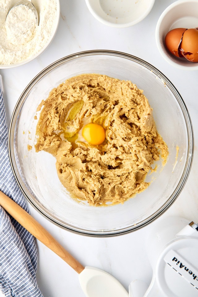 overhead view of egg added to creamed butter and sugar in a glass mixing bowl