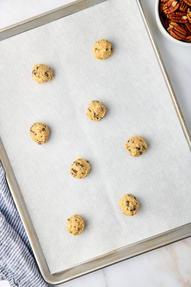 overhead view of scooped cookie dough on a parchment-lined baking sheet