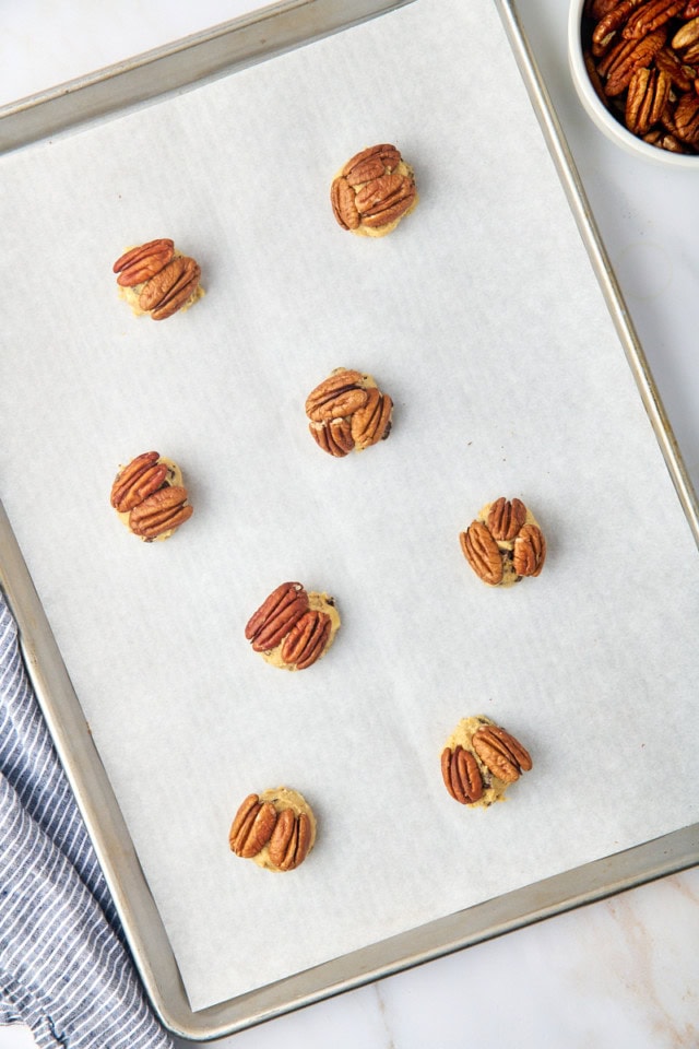 overhead view of triple chocolate pecan cookies on a parchment-lined baking sheet ready to go into the oven