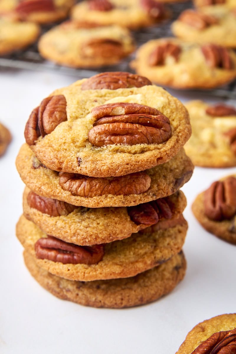 stack of five triple chocolate pecan cookies surrounded by more cookies