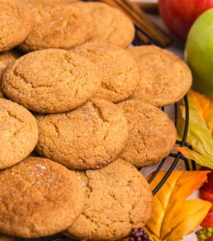 apple butter snickerdoodles on a wire rack surrounded by apples and fall leaves