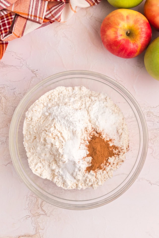 overhead view of flour, baking soda, cream of tartar, baking powder, salt, and cinnamon in a glass mixing bowl