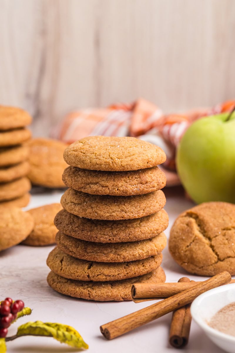 stack of several apple butter snickerdoodles with more cookies and apples in the background
