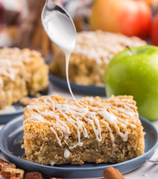 a slice of apple crumb sheet cake on a plate with glaze being drizzled over the top
