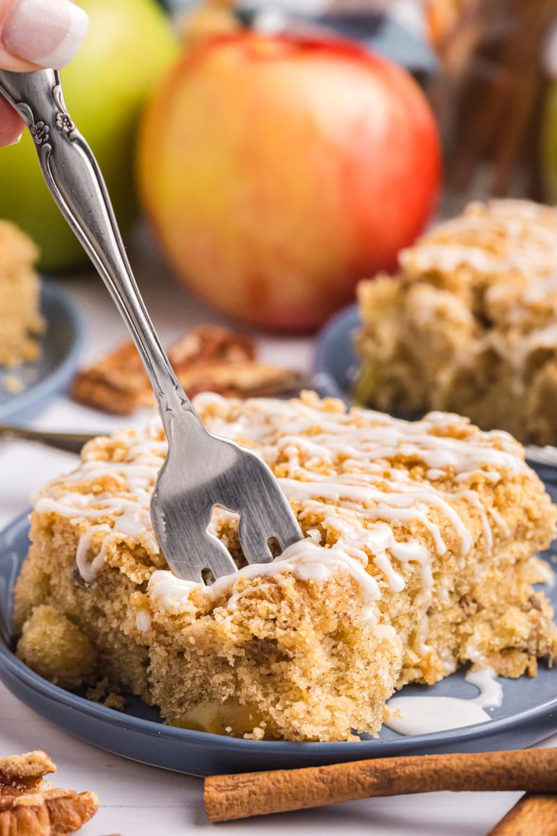 a slice of apple crumb sheet cake on a plate with a fork cutting into it