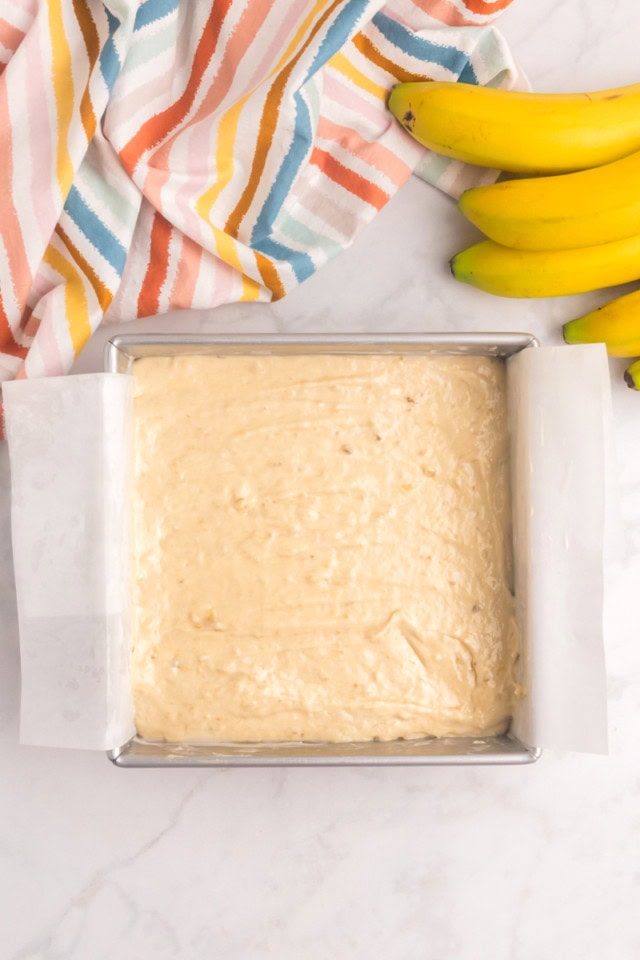 overhead view of banana cake in a parchment-lined baking pan ready to go into the oven