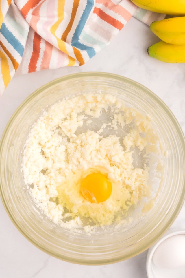 overhead view of egg added to creamed butter and sugar
