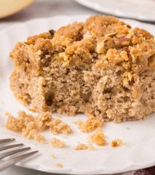 a slice of caramel apple crumb cake with a bite missing, served on a white plate