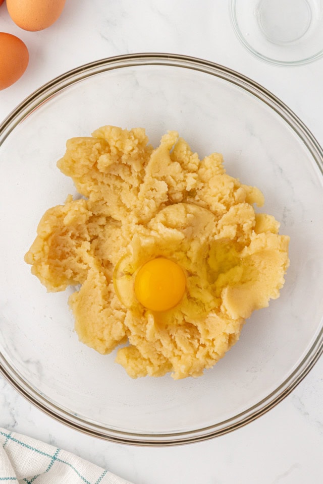 overhead view of egg added to choux pastry dough