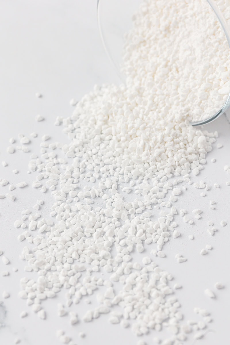 pearl sugar spilled out of clear jar onto a white surface